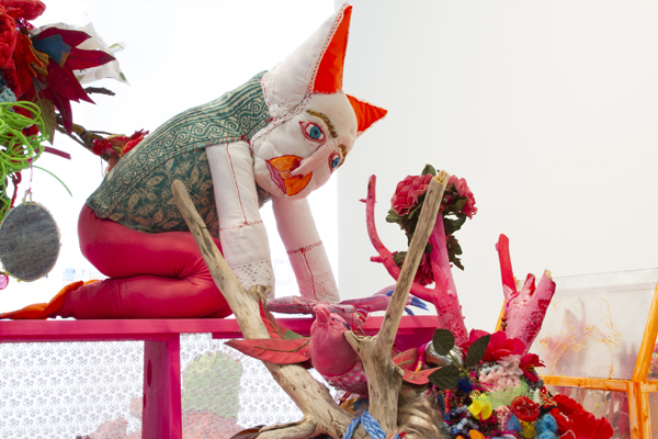 En varelse i tyg sitter framåtlutad på ett bord