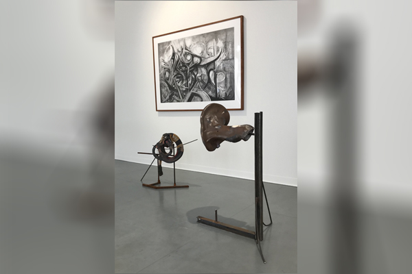 Två mörka skulpturer och en svartvit tavla