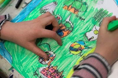 Speglingar Händerna hos ett barn som ritar en teckning.