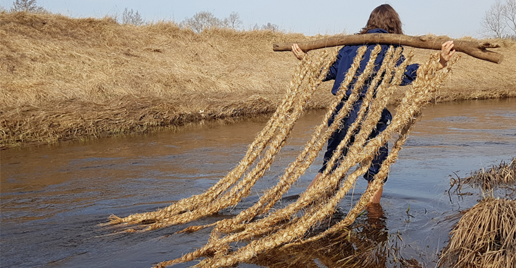 Kvinna med stock på axeln som det hänger rep ifrån.