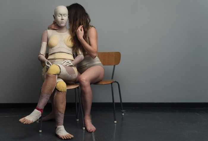 Stor docka och person sitter på stolar bredvid varandra