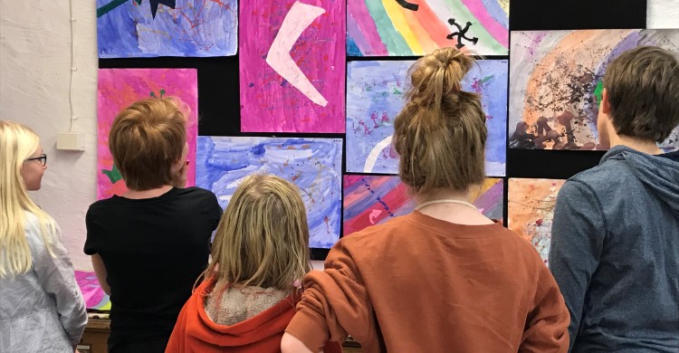 Några barn står och tittar på sina målningar